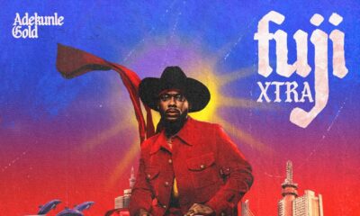 The official album cover for Adekunle Gold’s Fuji Xtra, featuring a surrealist design with the artist in a red suit and cowboy hat overlooking a city landscape.