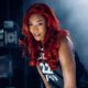 Las Vegas Aces basketball player A'ja Wilson wearing her black number 22 jersey, showcasing a long, vibrant red wavy hairstyle during a professional sports portrait session.