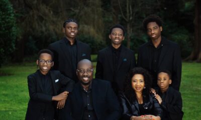 Close-up portrait of Obi Cubana and Ebele Iyiegbu seated with their five sons in coordinated black formal wear for a family photoshoot.