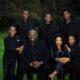 Close-up portrait of Obi Cubana and Ebele Iyiegbu seated with their five sons in coordinated black formal wear for a family photoshoot.