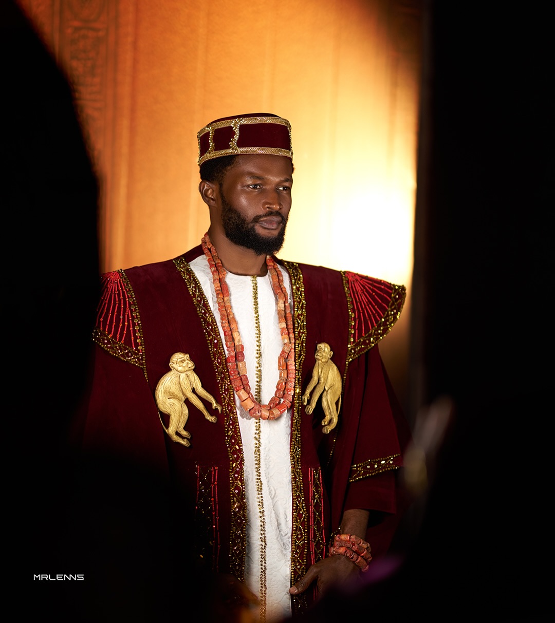 Bucci Franklin in a wine velvet cultural ensemble designed by Amy Aghomi featuring gold monkey motifs and coral beads for the AMVCA 12 Cultural Night.