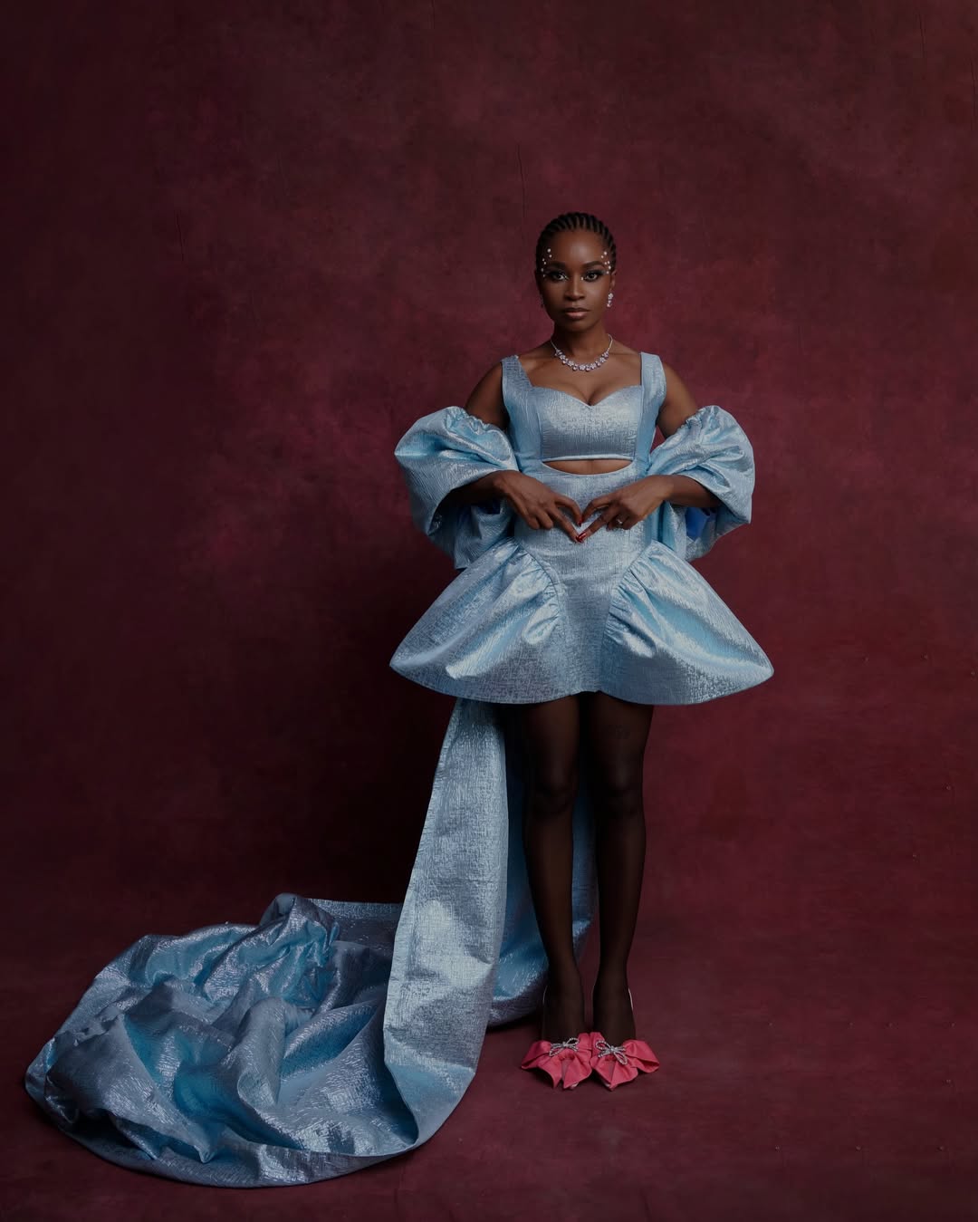 Uzoamaka Power wearing a structured iridescent powder blue gown with a long train at a film premiere.
