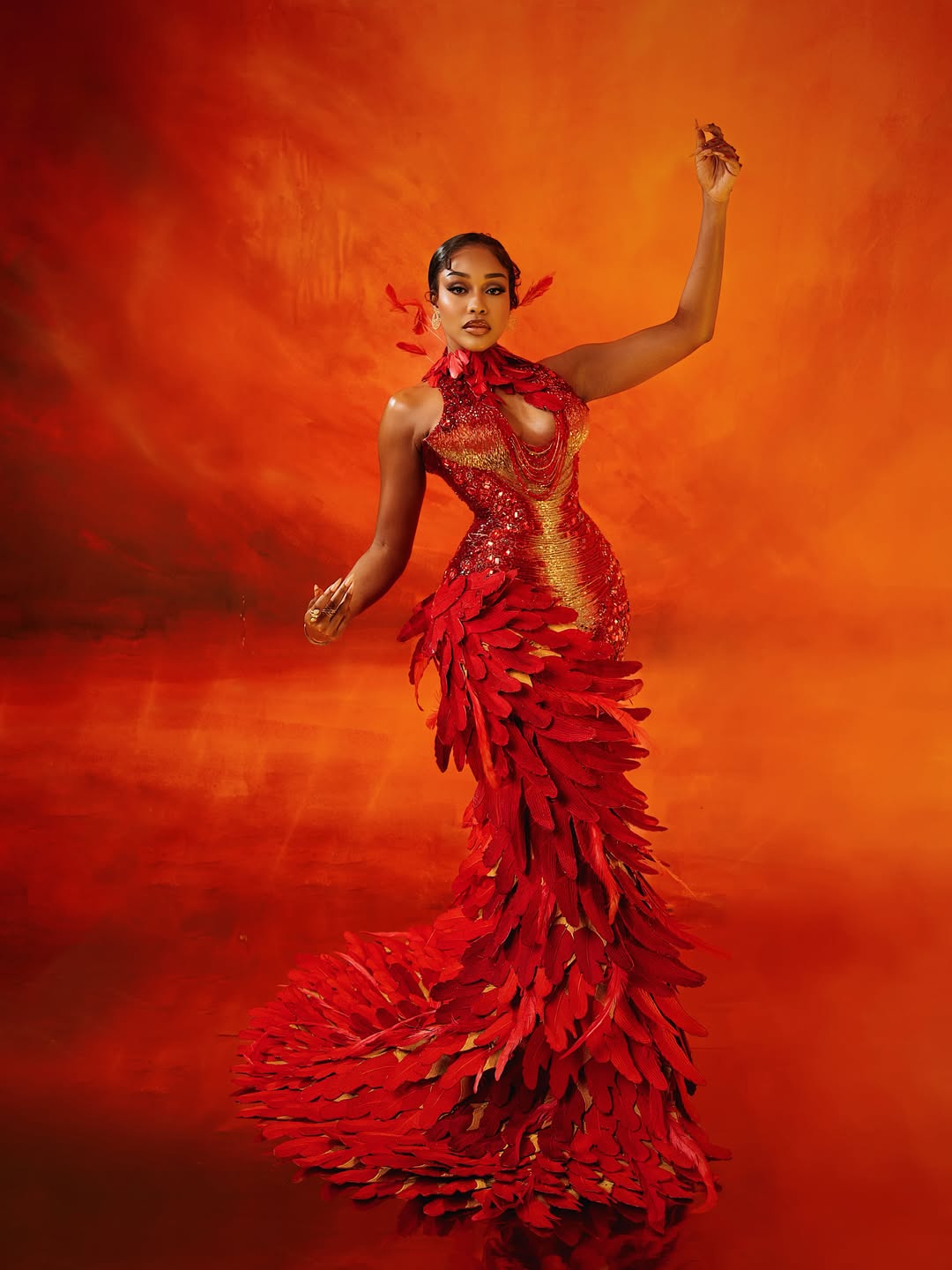 Nollywood actress Uche Montana posing in a custom red and gold feathered Tubo gown on the AMVCA 2026 red carpet.