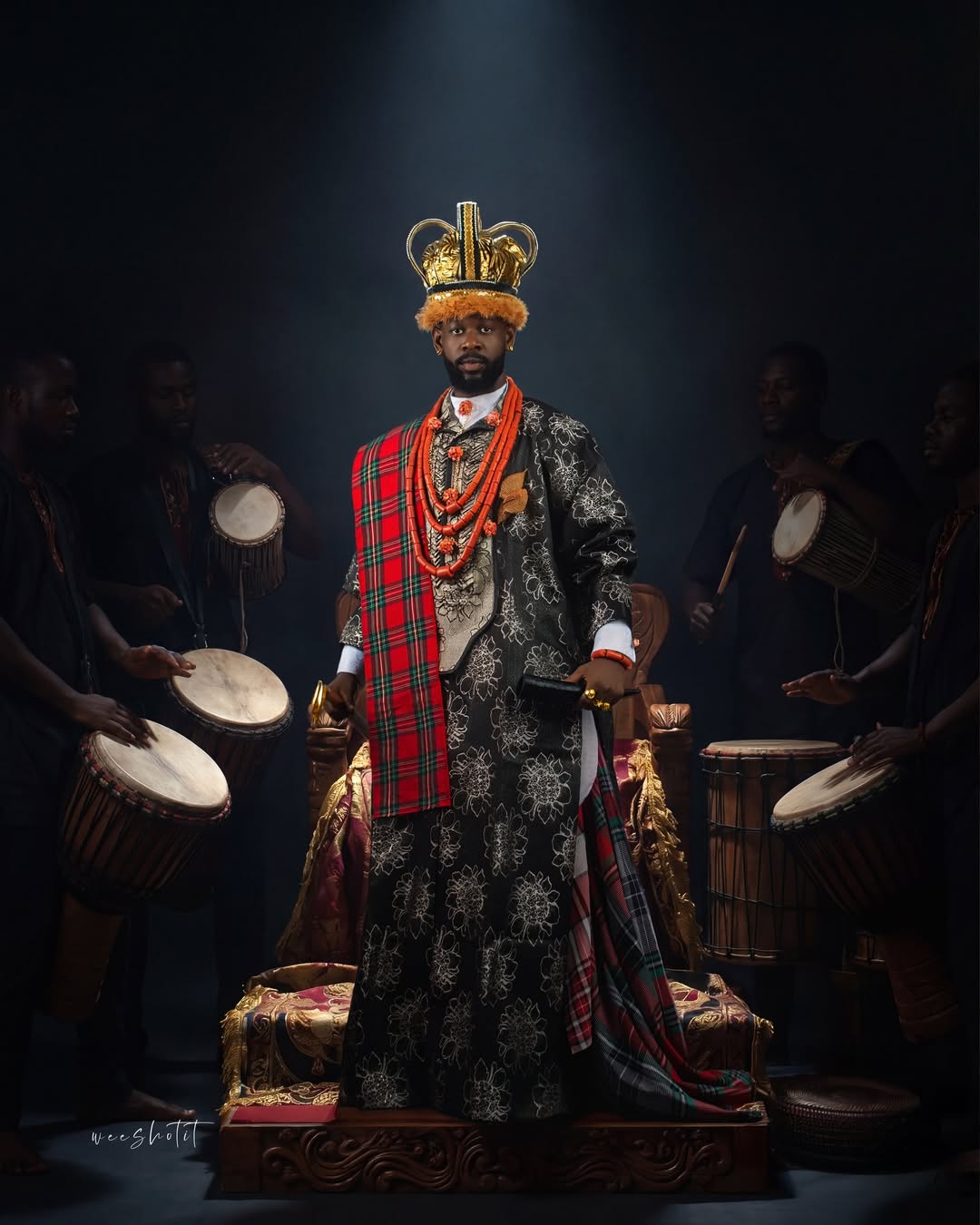 Mensan in an Ijaw Prince attire featuring a black and silver brocade robe and George fabric for AMVCA 12.