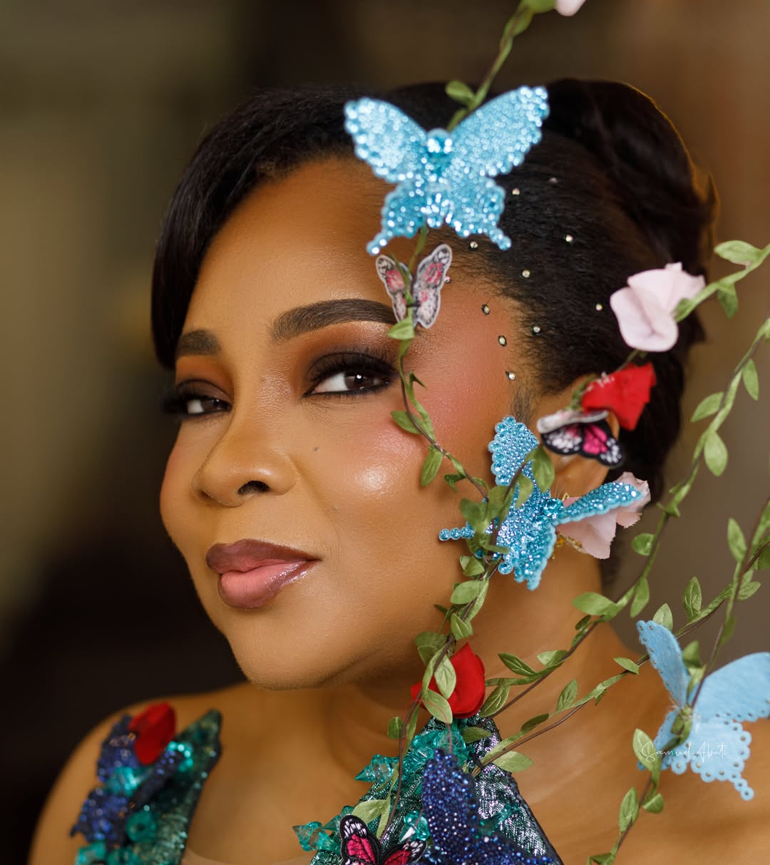 A close-up portrait of Linda Ejiofor-Suleiman featuring butterfly hair ornaments and soft glam makeup for the 2026 AMVCA.
