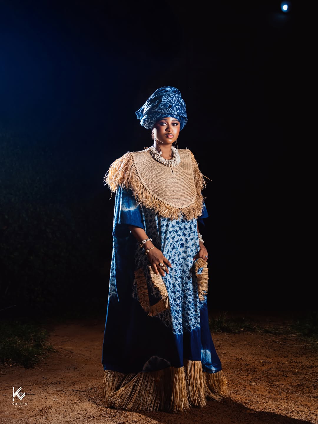 Imisi in a blue and white Adire gown with a cowrie shell crown and straw fringe for AMVCA 12.