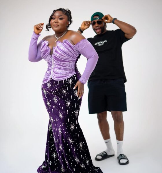 Blessing Nze in a purple velvet mermaid gown with silver starburst embellishments, with husband Stan Nze visible in the background.