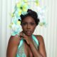 Close-up portrait of Beverly Osu showing her floral headpiece, teal lace corset, and glowy makeup for the Call of My Life premiere.