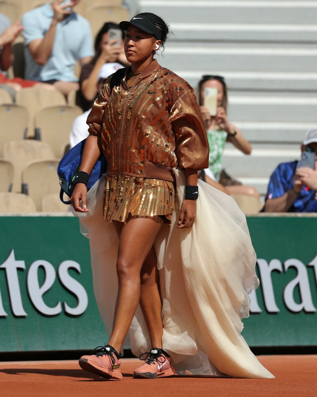 Naomi Osaka walks onto Court Simonne-Mathieu in a gold sequined bomber jacket and ivory tulle train for her second-round French Open 2026 match against Donna Vekić on 28 May