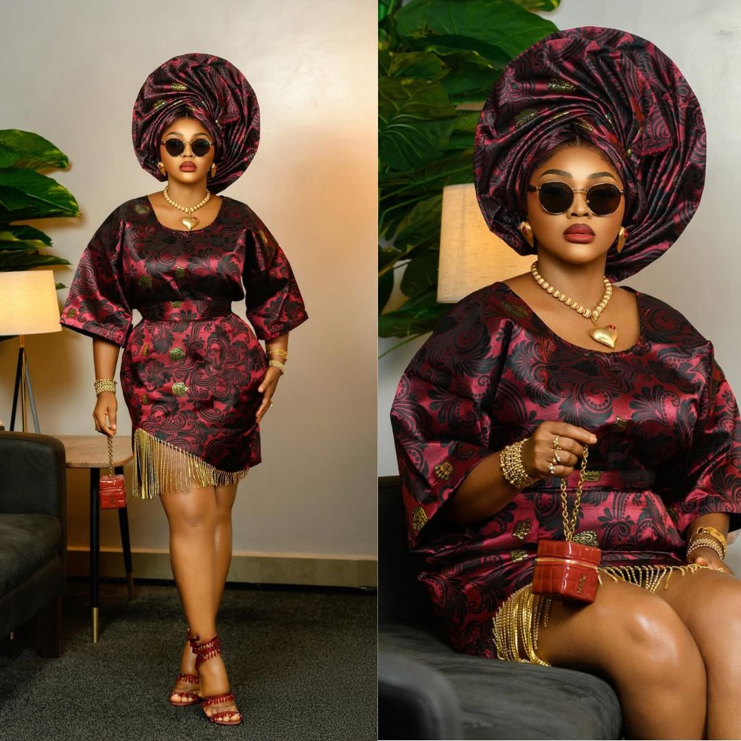 Actress Mercy Aigbe in a rich burgundy and black patterned damask Oleku with a gold fringe hemline and matching dark sunglasses.