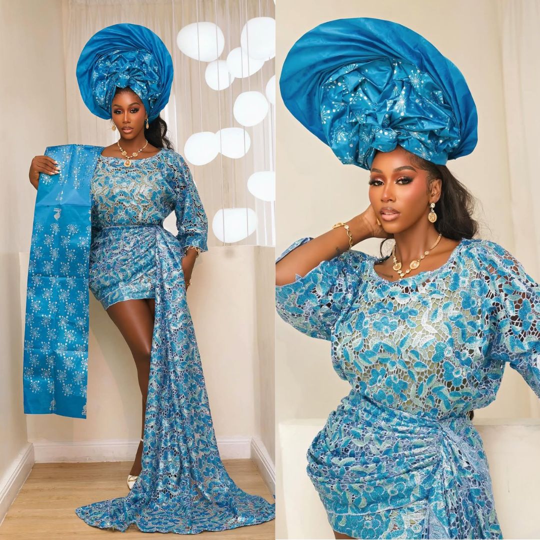 Nelly Mbonu posing in a bright blue lace traditional Oleku outfit with an elongated side train and a matching voluminous structured gele.