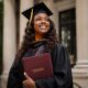 An AI-generated image of a smiling Black woman in a black academic graduation gown and cap, holding a certificate folder outdoors in front of a university building