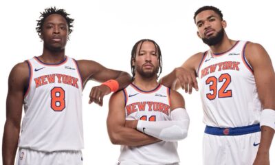 New York Knicks players OG Anunoby, Jalen Brunson, and Karl-Anthony Towns posing together in their white home jerseys.
