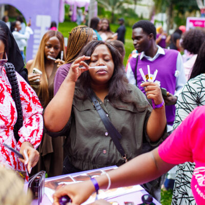 Shoppers queue under umbrellas in the rain at Beguile's Summer Has a Scent pop-up in Abuja
