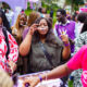 Shoppers queue under umbrellas in the rain at Beguile's Summer Has a Scent pop-up in Abuja