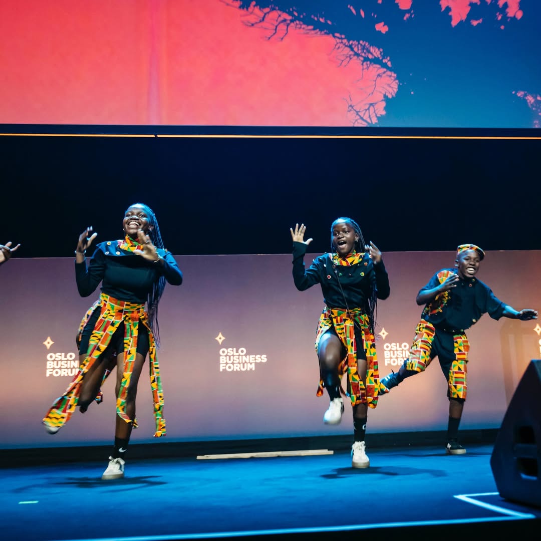 Three members of the Ugandan dance group Ghetto Kids executing a synchronised mid-air dance routine on stage at the Oslo Business Forum.