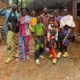 Members of the Ghetto Kids posing outdoors in vibrant, multi-coloured graphic print suits and statement sunglasses.