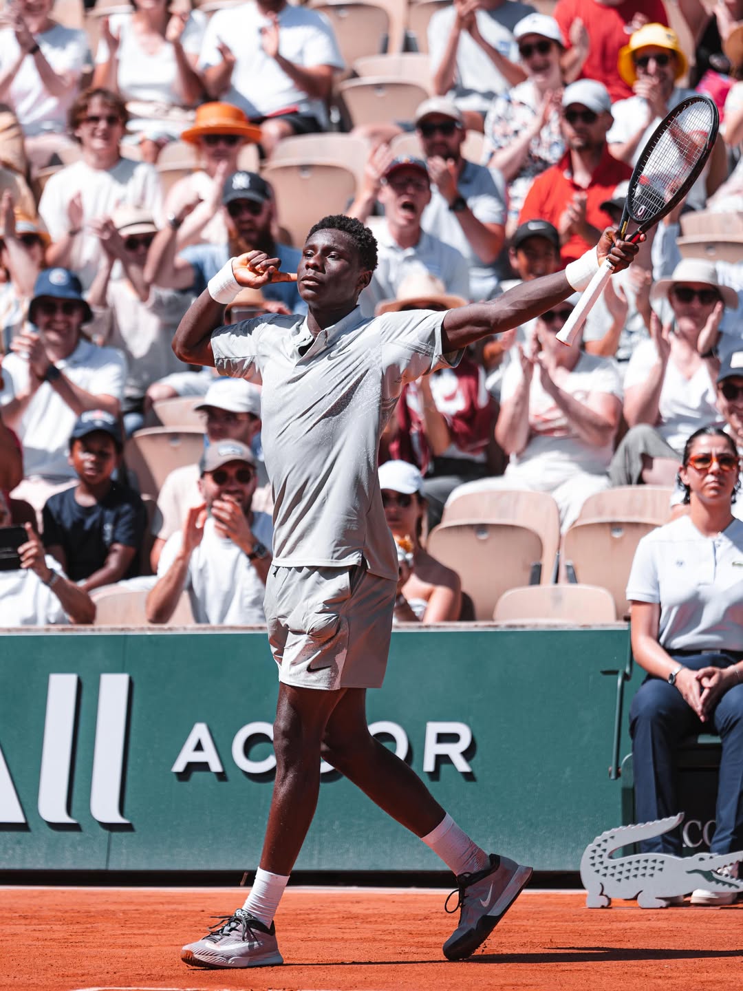 French-Ivorian tennis player Moise Kouame celebrating a point with his arm raised on the clay court during his first-round match at the 2026 French Open.