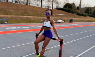 Nigerian world record holder Tobi Amusan sitting on a hurdle at a running track during a practice session.