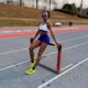 Nigerian world record holder Tobi Amusan sitting on a hurdle at a running track during a practice session.