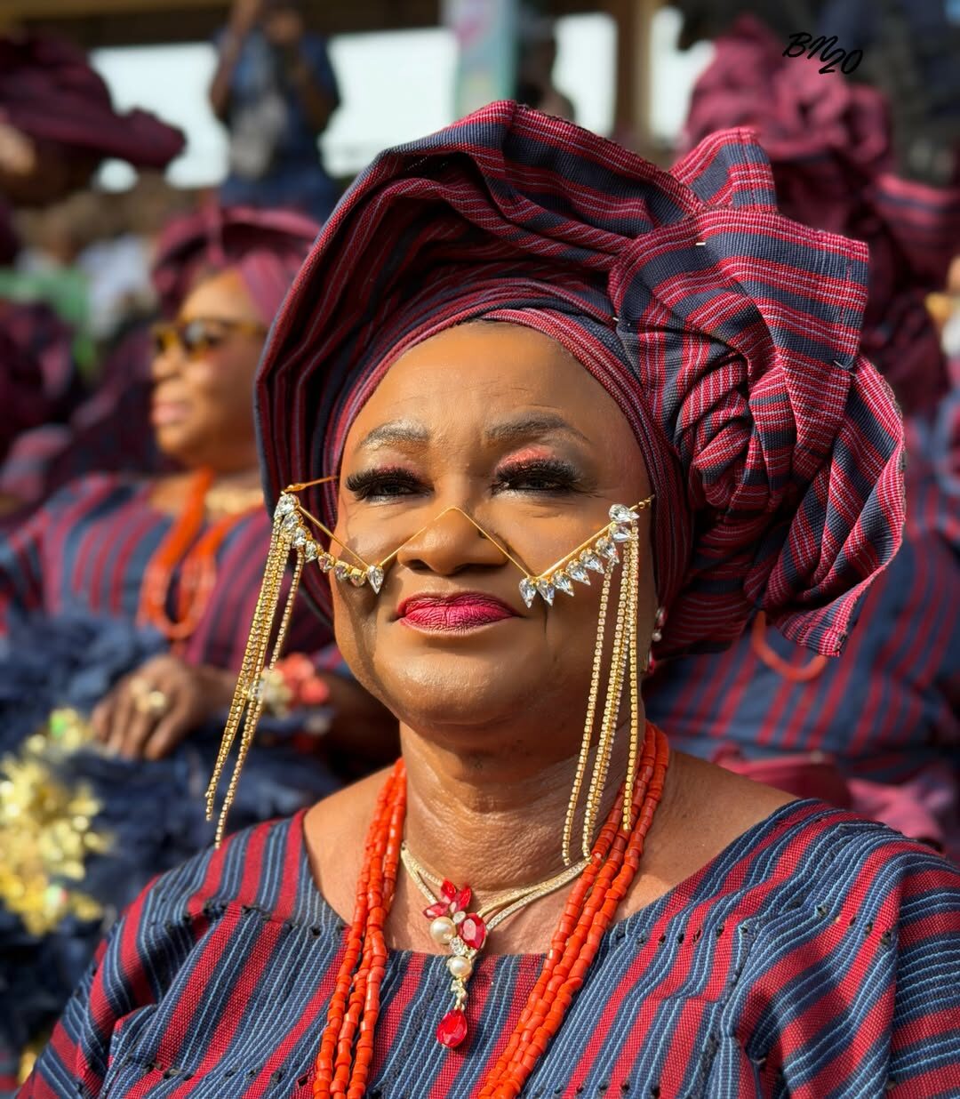 A woman at Ojude Oba 2026 wearing a frameless eyewear piece constructed entirely of gold chains and hanging crystals draped across her nose and cheeks.