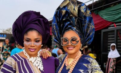 Nollywood actresses Eniola Ajao and Mercy Aigbe in traditional Yoruba Aso Oke and elaborate geles wearing statement sunglasses on the set of Iwe Ala.