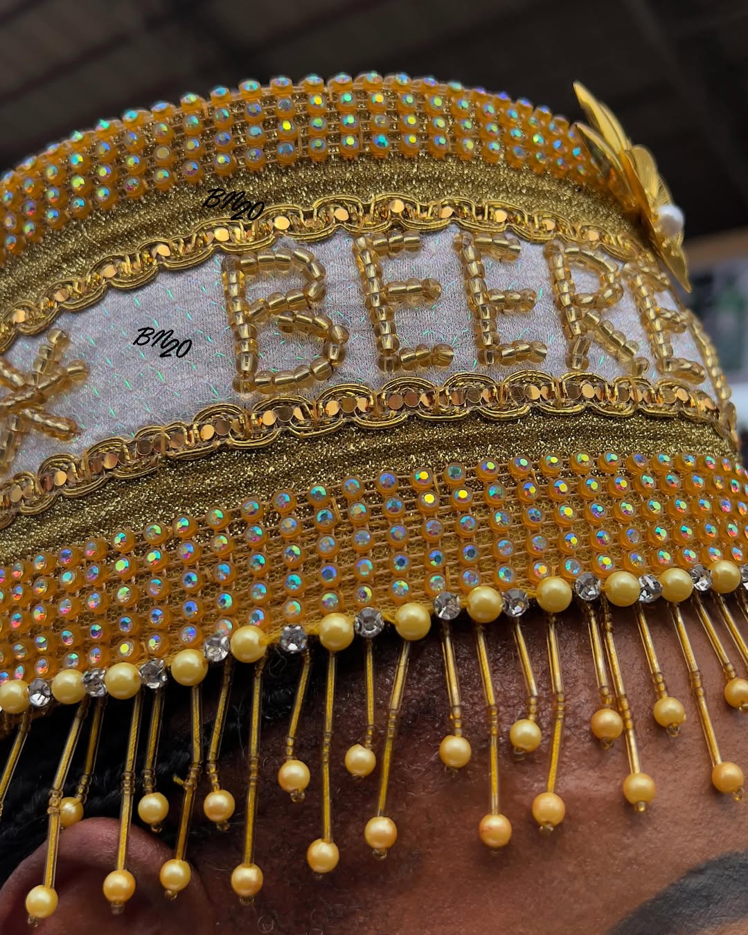 A close-up of a golden traditional Yoruba crown heavily detailed with yellow beads, rhinestones, and hanging bead fringes at the Ojude Oba Festival.
