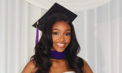 Chioma Amadi smiling in a white strapless dress with her black Savannah College of Art and Design graduation gown draped loosely over her arms.