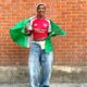 Afrobeats artist Tiwa Savage smiling while holding open the green and white Nigerian flag over her shoulders during the Arsenal trophy celebration in London.