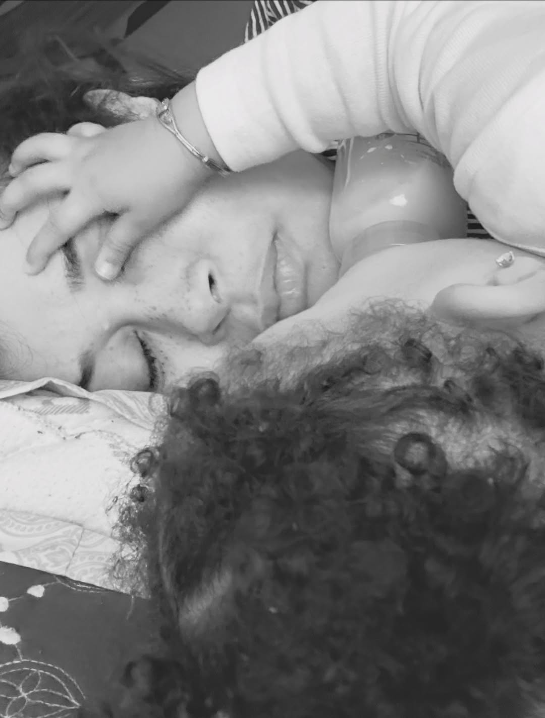 Black and white close-up photo of Nigerian actress Adunni Ade sleeping in bed while cuddling her baby girl, Baby Sal.