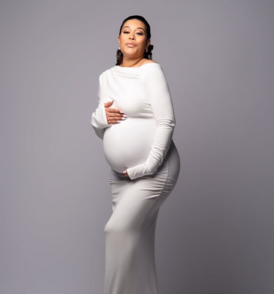 maternity shoot of Nollywood actress Adunni Ade wearing a form-fitting white long-sleeved dress and cradling her baby bump.