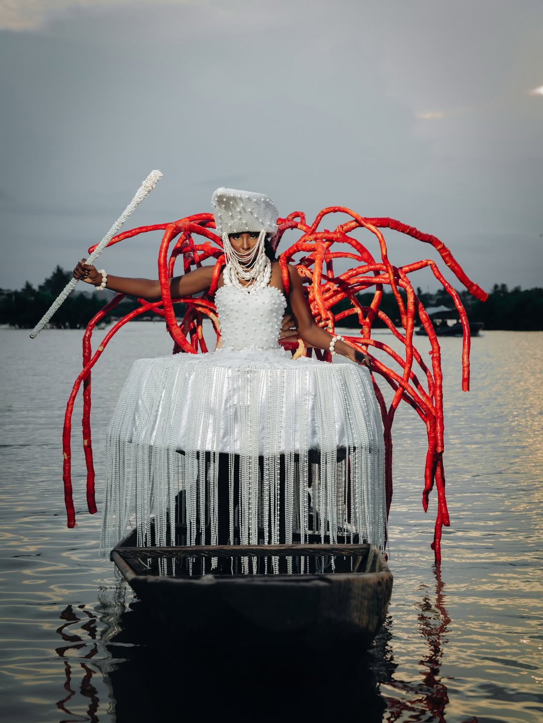 Tamunosoye Karibi George standing in water, wearing a white beaded and coral-inspired structural national costume themed Amazon of the Mangrove.