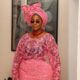 Portrait of Hilda Baci highlighting her sheer pink floral lace buba bodice, chunky red coral bead necklace, and retro sunglasses, styled by Emmanuel Goodnews.