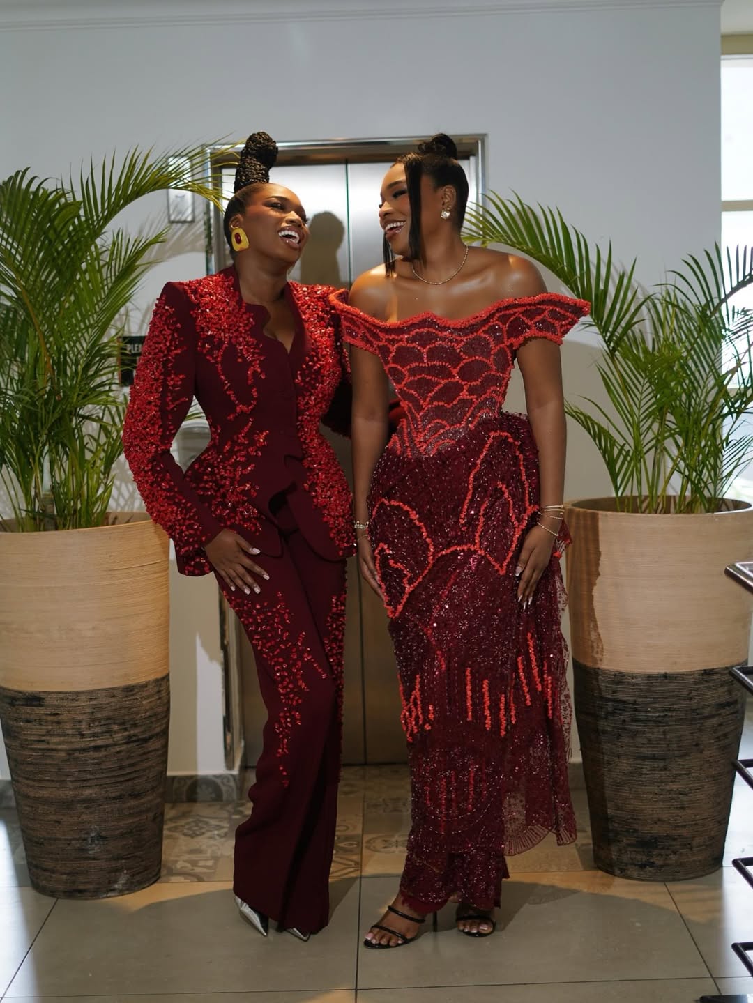 Sabrina Idukpaye laughing next to Thelma Lawson in a coordinated wine-red dress at the BBNaija reunion.