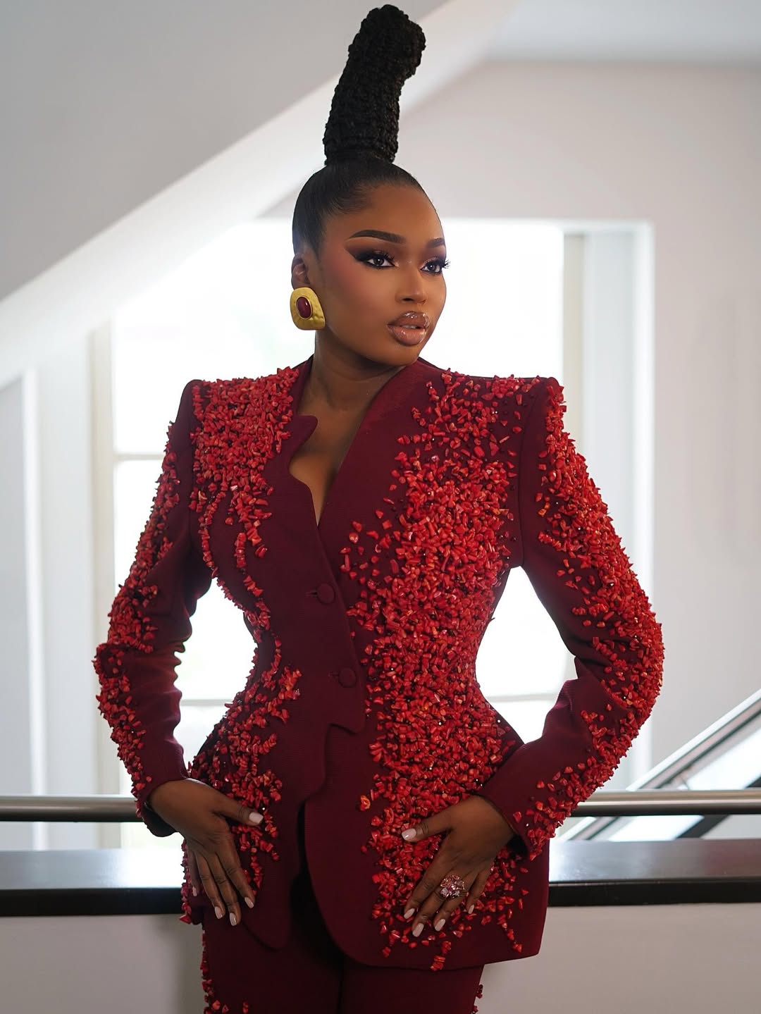 Sabrina Idukpaye wearing a structured burgundy blazer embellished with clusters of red coral-like stones.