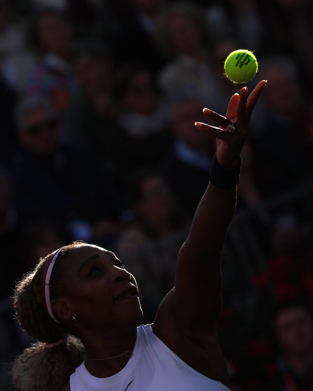 Close-up of Serena Williams tossing a tennis ball in the air to serve during her grass-court comeback match.