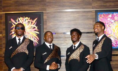 Four DR Congo players standing indoors in matching black-tie suits with leopard details and dark sunglasses.