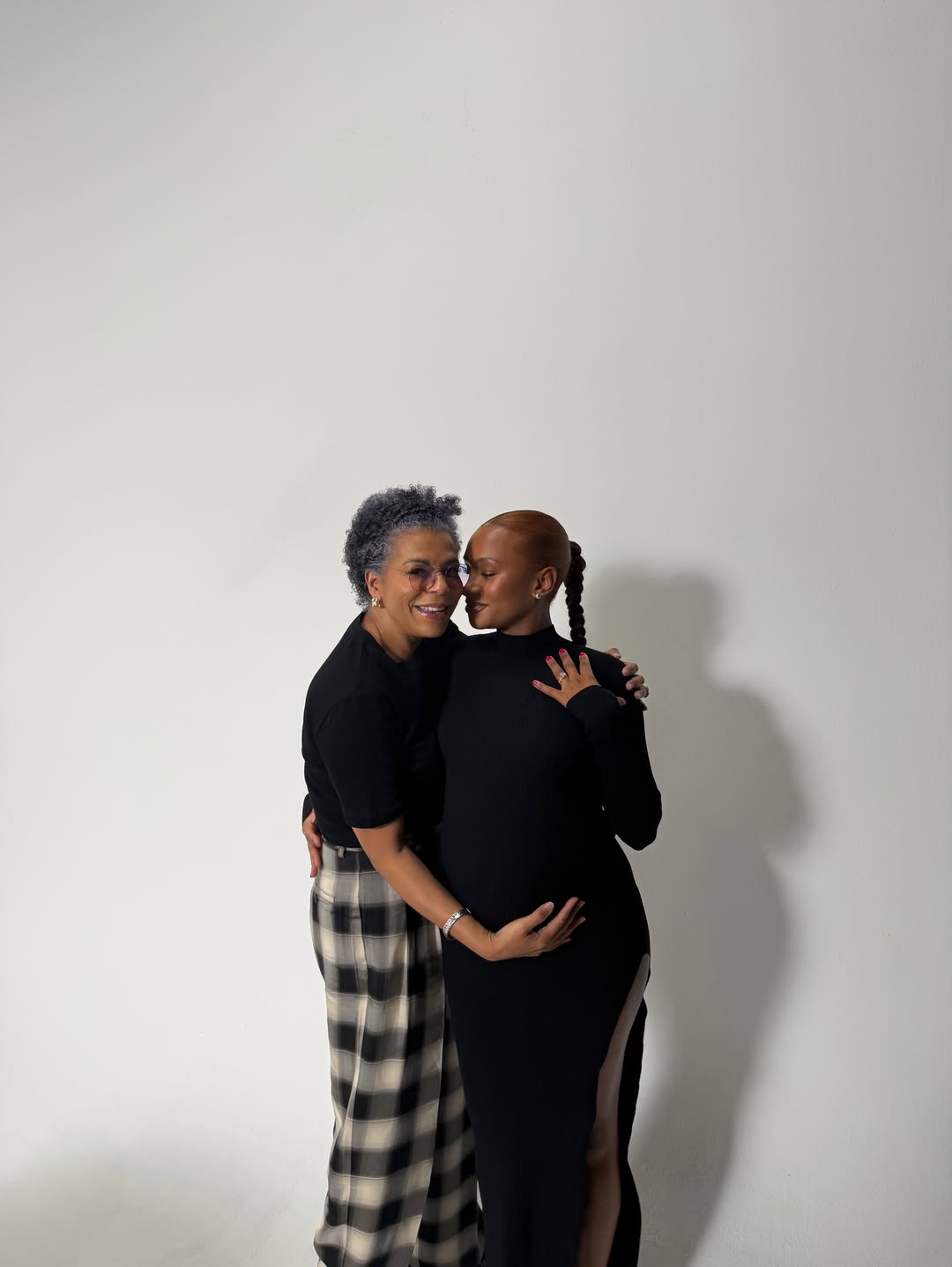 Temi Otedola embraces her mother Nana Otedola against a plain white studio backdrop.