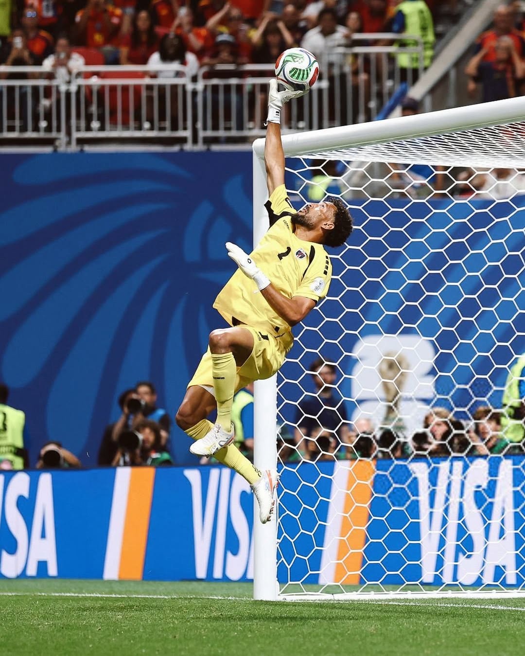 abo Verde goalkeeper Vozinha leaping into the air next to the crossbar to tip a football over the goal net.