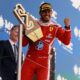 Lewis Hamilton raises his fist in victory and holds up his gold first-place trophy on the podium in Barcelona.