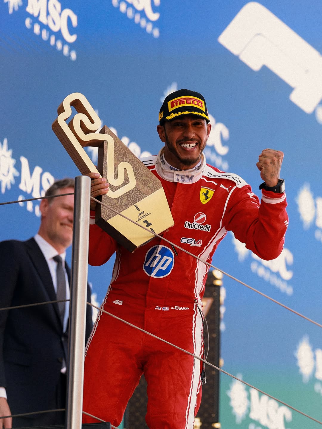 Lewis Hamilton raises his fist in victory and holds up his gold first-place trophy on the podium in Barcelona.