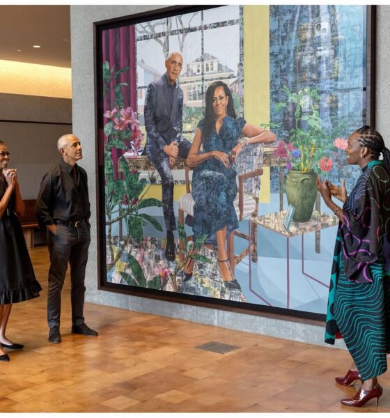 Barack and Michelle Obama stand in a gallery looking at their large-scale joint portrait while Nigerian artist Njideka Akunyili Crosby gestures and speaks.