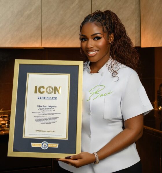 A portrait of Nigerian culinary star Hilda Baci in a white chef top presenting her official framed Guinness World Records Icon certificate.