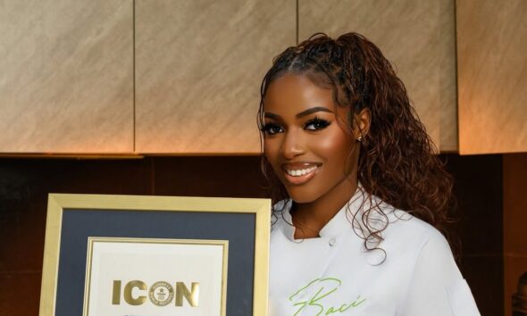 A portrait of Nigerian culinary star Hilda Baci in a white chef top presenting her official framed Guinness World Records Icon certificate.