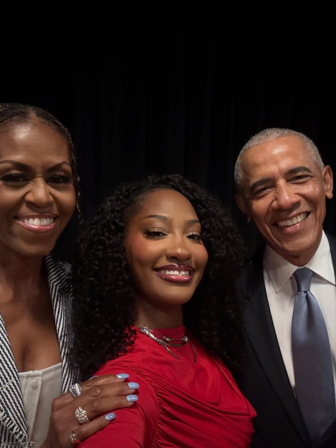 Smiling selfie featuring Michelle Obama, Nigerian musician Tems, and former US President Barack Obama together at the Obama Presidential Center in Chicago.