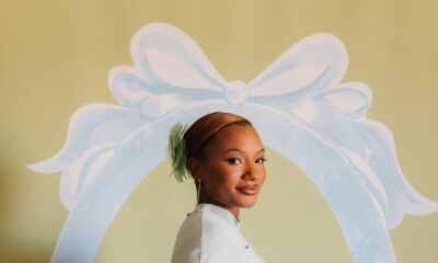 Temi Ajibade cradling her pregnancy baby bump while wearing a mint-tinted ice blue silk maternity gown with a matching cape at her swan-themed baby shower.