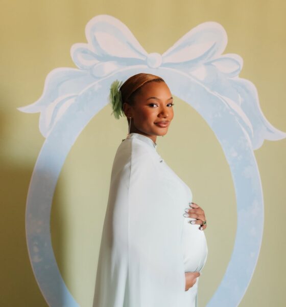 Temi Ajibade cradling her pregnancy baby bump while wearing a mint-tinted ice blue silk maternity gown with a matching cape at her swan-themed baby shower.