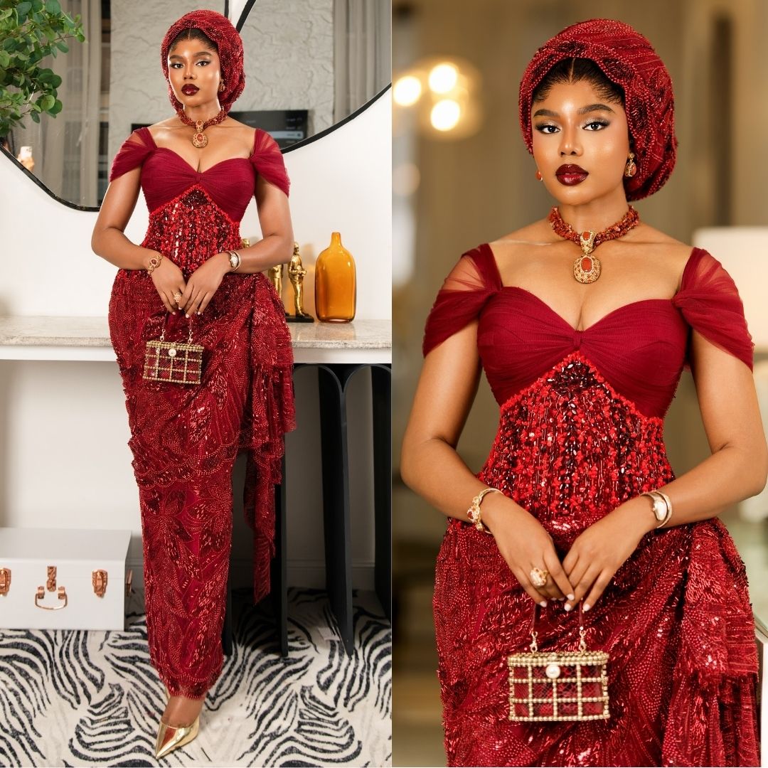 Nancy Isime in an off-the-shoulder crimson gown with a gathered tulle bust, heavily beaded corset bodice, structured hip drape, and matching beaded gele.