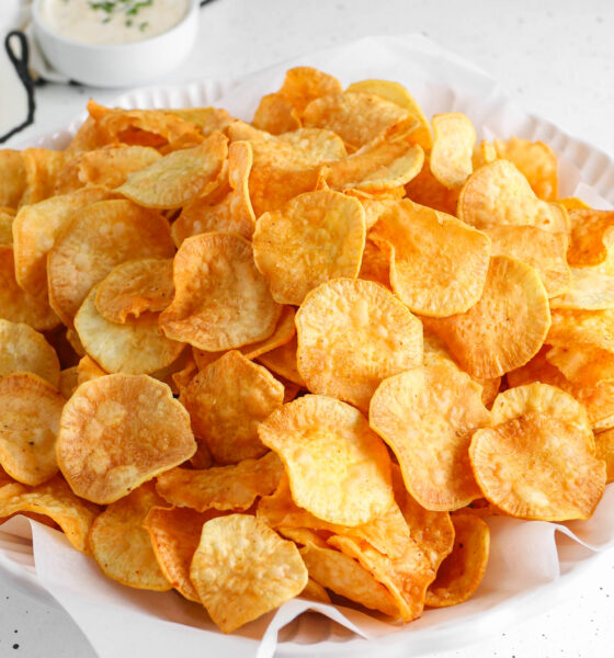 A white bowl filled with crunchy, golden-brown homemade sweet potato chips made from Nigerian white sweet potatoes, served with a side dip.