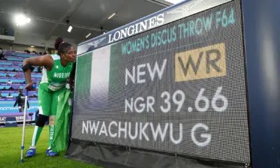 Goodness Nwachukwu posing beside the Longines scoreboard displaying her 39.66m F42 discus world record at Glasgow 2026.